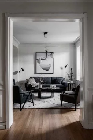 A beautifully designed minimalist living room. The room should be well lit, have clean lines, a monochromatic color scheme with subtle textures, carefully chosen modern furniture pieces, and minimal but impactful decor. The space should look inviting, masculine, and perfectly curated.