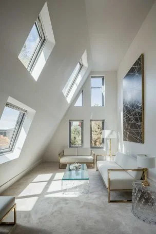 A bright, airy tiny living room with high ceilings, featuring a small white sofa, glass coffee table, and large windows. The room should have a minimalist yet elegant feel, with touches of gold accents and a single piece of modern art on the wall.