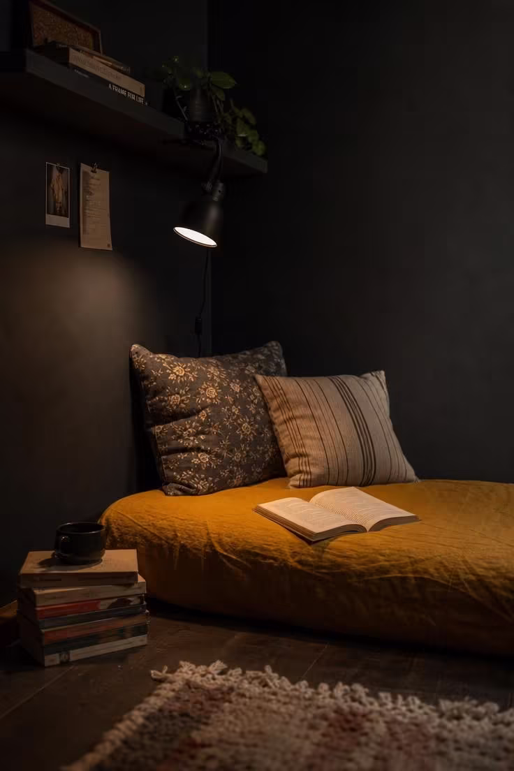 13 Cozy Apartment Reading Nook Ideas for Small Spaces 2 Dark charcoal chalk-painted apartment corner with a mustard linen floor mattress and clip-on reading lamp