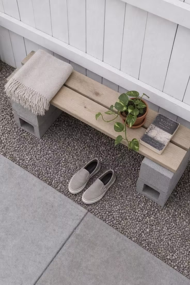 13 Clever Backyard Ideas on a Budget That Feel Polished 2 Overhead view of a cinderblock and pine plank bench along a white painted fence on a hazy overcast morning