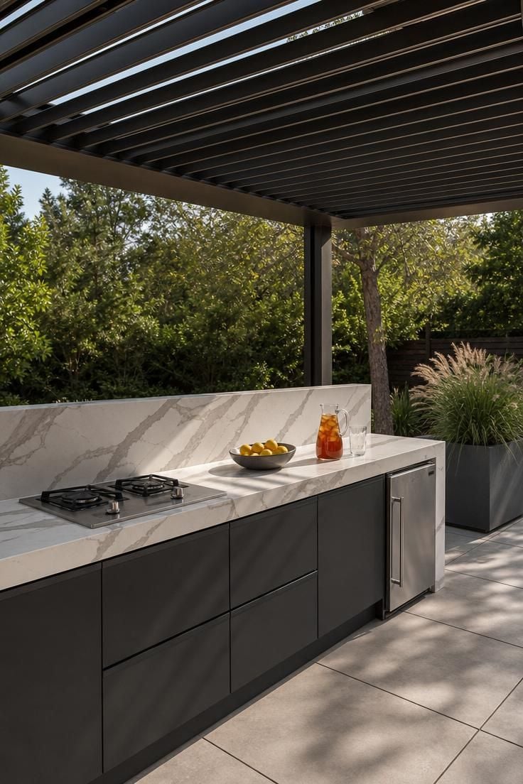 Modern outdoor kitchen with porcelain slab counters under motorized louvered shade panels in soft diffused light