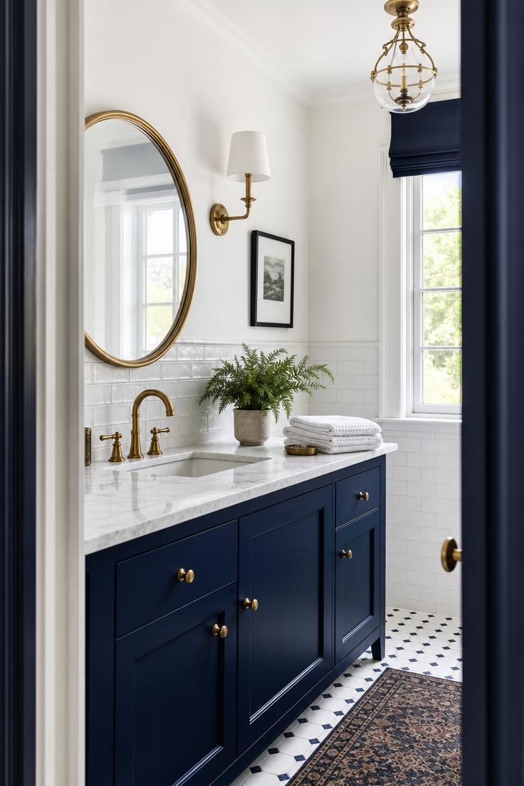 Navy bathroom vanity with white subway tile and unlacquered brass faucet.