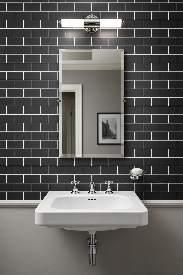 Matte charcoal subway tile wall with bright white grout lines behind a white wall-mounted sink and frameless mirror