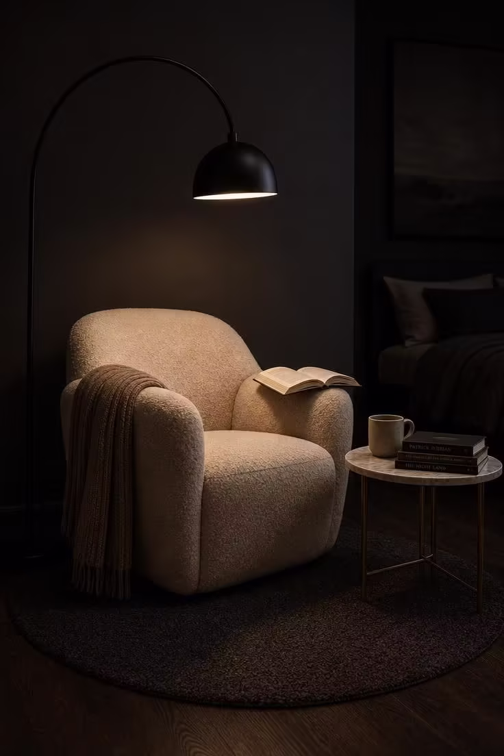 13 Cozy Bedroom Reading Nook Ideas for Quiet Evenings 3 A cream boucle armchair under a matte black arc lamp in a charcoal-painted bedroom corner with a marble side table and wool throw