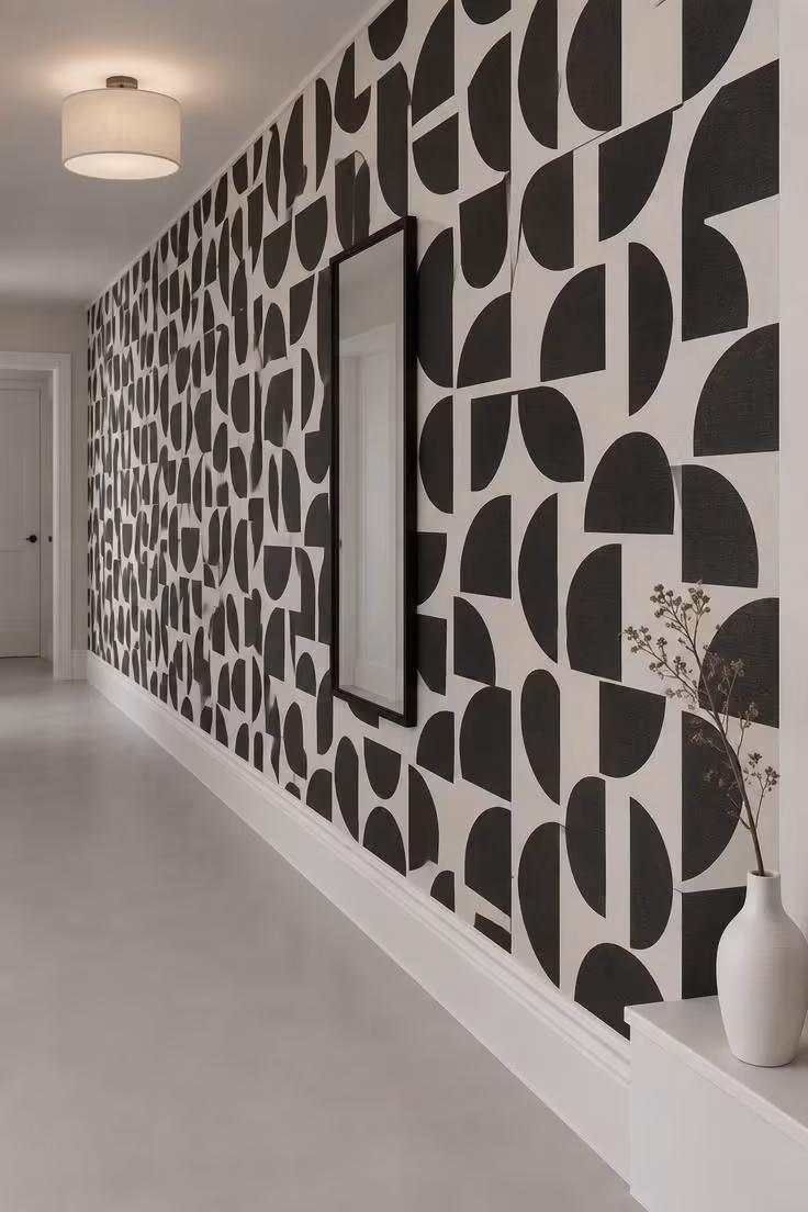 13 Warm Black and White Hallway Ideas for a Bold Entry 5 A bold black-and-white geometric wallpaper covering one long hallway wall with plain white trim and a quiet pale floor.