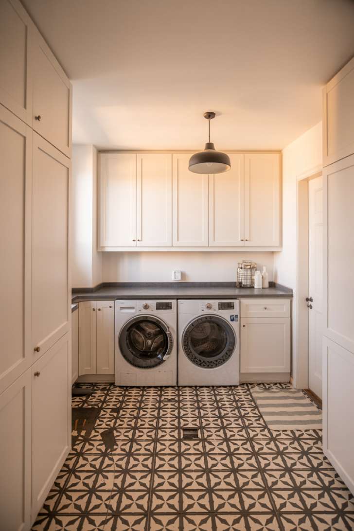 Modern laundry room with black and white geometric patterned cement tile floor and white flat-panel cabinets