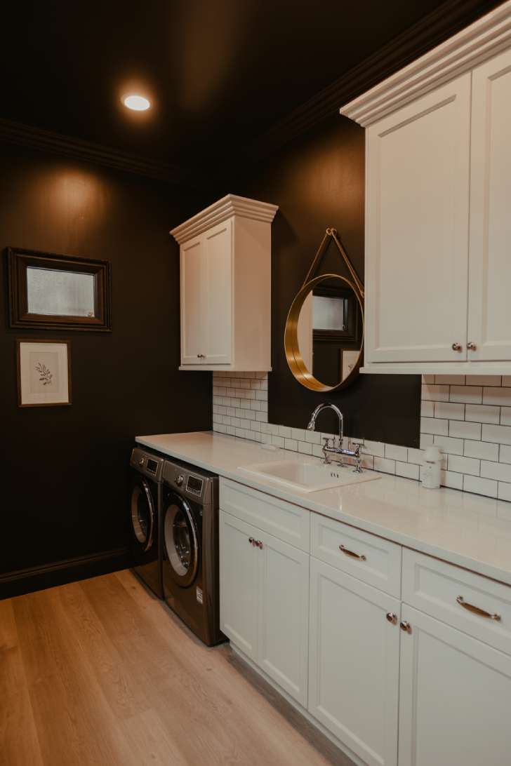 11 Chic Black Laundry Room Ideas That Elevate Your Space 3 Black painted walls with white cabinets and brass mirror in a sophisticated laundry room