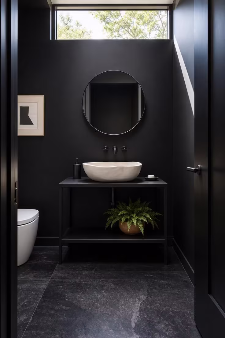 11 Bold Black Powder Room Ideas for a Moody Retreat 4 Honed black granite floor powder room with white plaster vessel sink and matte black walls in bright midday light