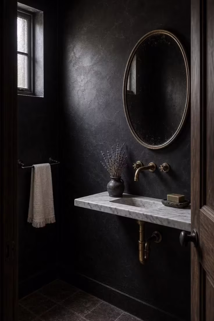 11 Bold Black Powder Room Ideas for a Moody Retreat 7 Black roman clay plaster powder room with slim marble ledge sink and hand-forged iron towel bar in cool overcast light