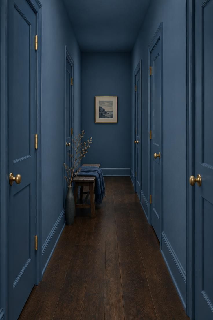 13 Brilliant Blue Hallway Ideas to Warm Your Entry 2 Narrow hallway with denim blue walls, ceiling, trim, and doors all in the same tone, unlacquered brass knobs, a dark wood floor, and a single framed print on the end wall.