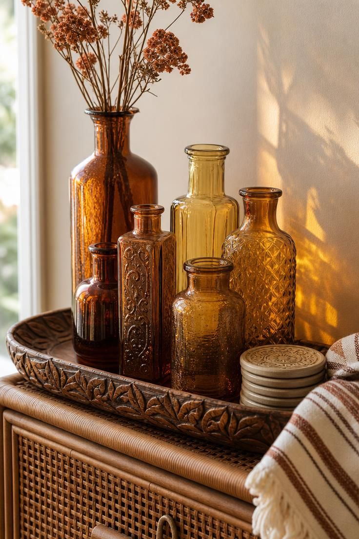 Amber glass bottles on a carved mango wood tray with dried florals, glowing in soft window light.
