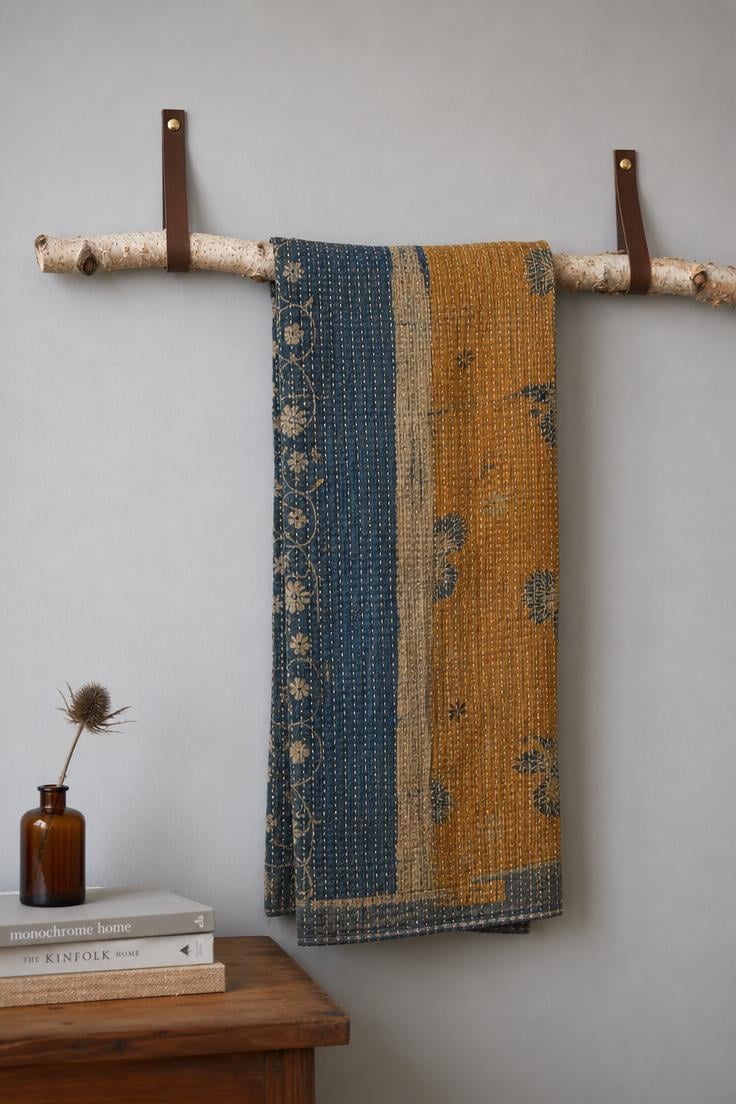 13 Beautiful Boho Wall Decor Ideas You Need to Try 8 Vintage kantha quilt runner in faded indigo and saffron draped over a birch branch rod mounted with leather straps