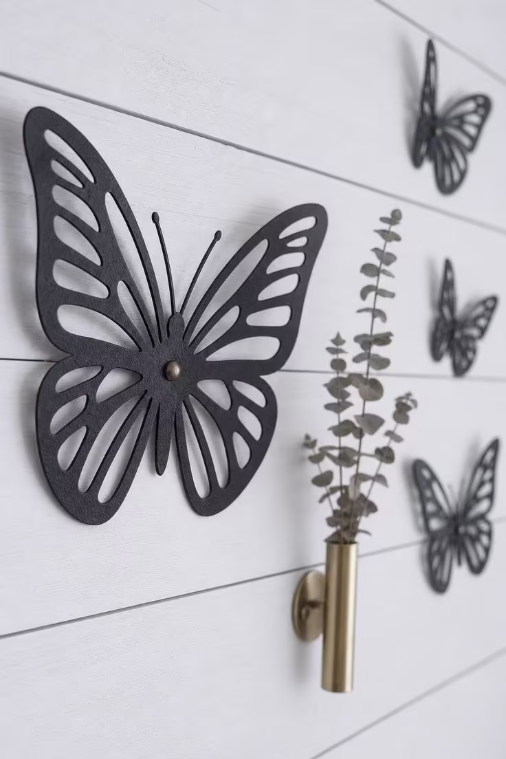 10 Fresh Butterfly Wall Decor Ideas to Brighten Walls 3 Close-up of a matte black iron butterfly silhouette with laser-cut wing details mounted on a white shiplap accent wall in cool overcast light.