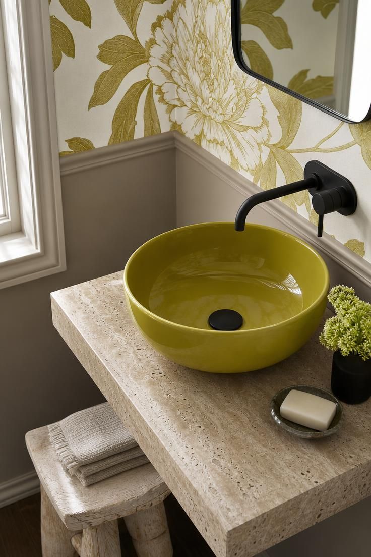 14 Colorful Eclectic Home Ideas for a Joyful Space 8 Chartreuse vessel sink on a travertine slab with a matte black faucet and floral wallpaper.