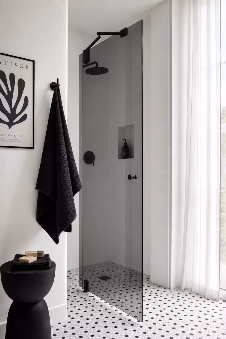 10 Corner Shower Ideas for Small Bathrooms That Feel Bigger 9 Corner shower with smoked glass door on a matte black pivot arm over micro-hex tile.
