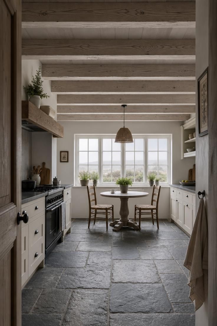 10 Charming Cottage Farmhouse Kitchen Ideas to Recreate 3 Wide view of a cottage farmhouse kitchen with whitewashed oak ceiling rafters, slate floor, and cool overcast light from divided-lite windows