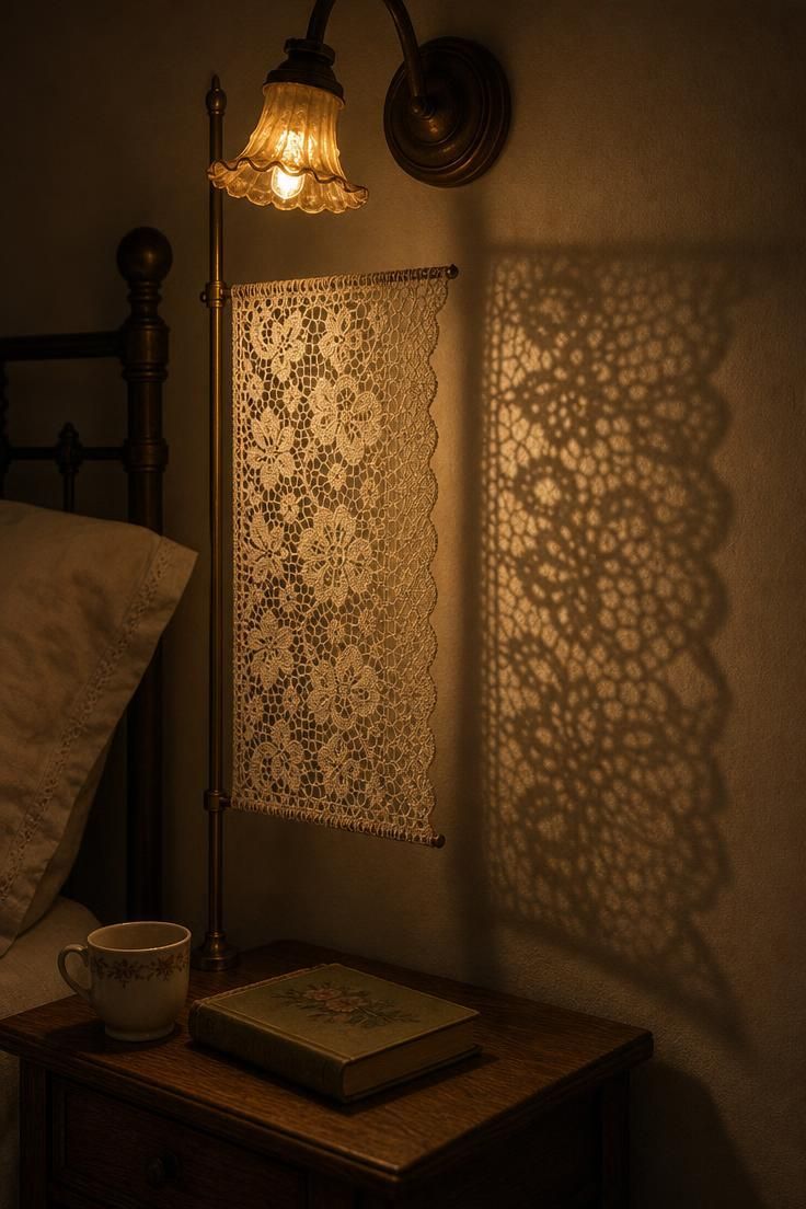 Vintage lace panel beside a bed with a warm sconce casting a patterned shadow through the lace.