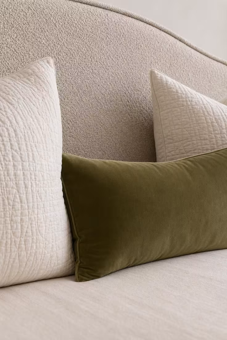 11 Warm & Inviting Cozy Fall Bedroom Retreat Tips Now 8 An olive green velvet lumbar pillow centered against a bouclé headboard with cream matelassé shams on each side.