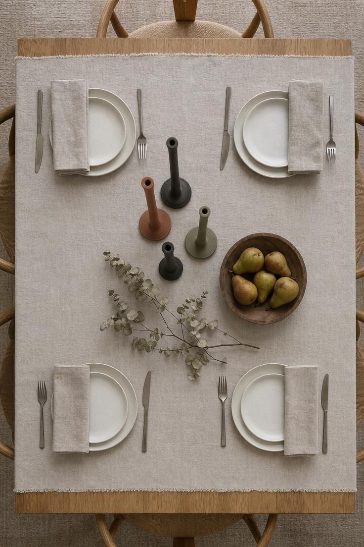 Cluster of mixed-height clay taper holders on an oak dining table in cool overcast light