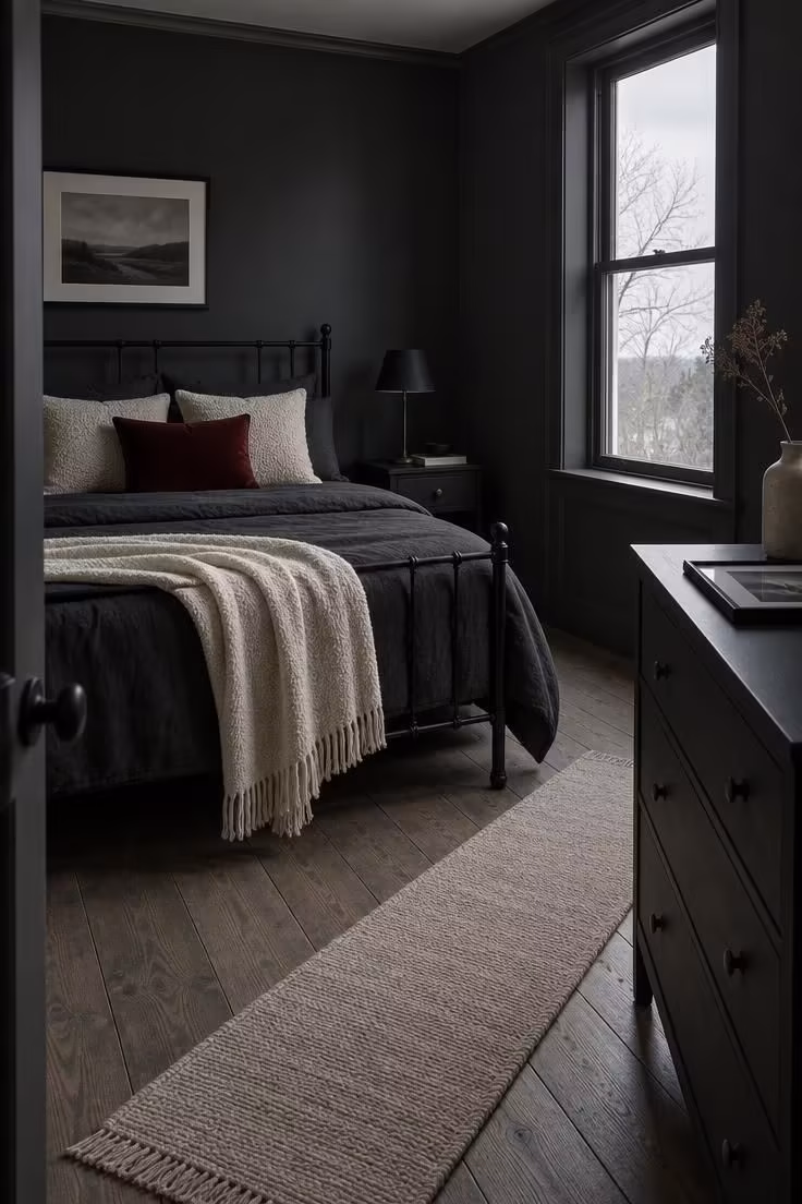 11 Cozy Halloween Bedroom Ideas for Calm Autumn Nights 5 Nearly monochrome bedroom in black and cream with a single oxblood velvet cushion on the bed.