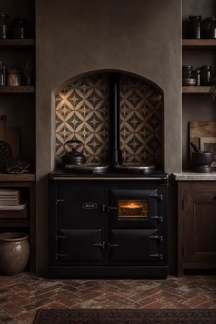 Cast-iron range in matte black set into a tiled alcove in a cottage kitchen with moody low light