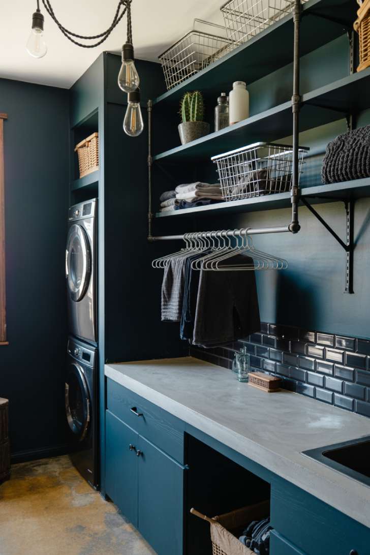 11 Beautiful Dark Laundry Room Ideas That Spark Instant Joy 7 Industrial dark teal laundry room with concrete countertop, black metal shelving, and Edison pendant lights