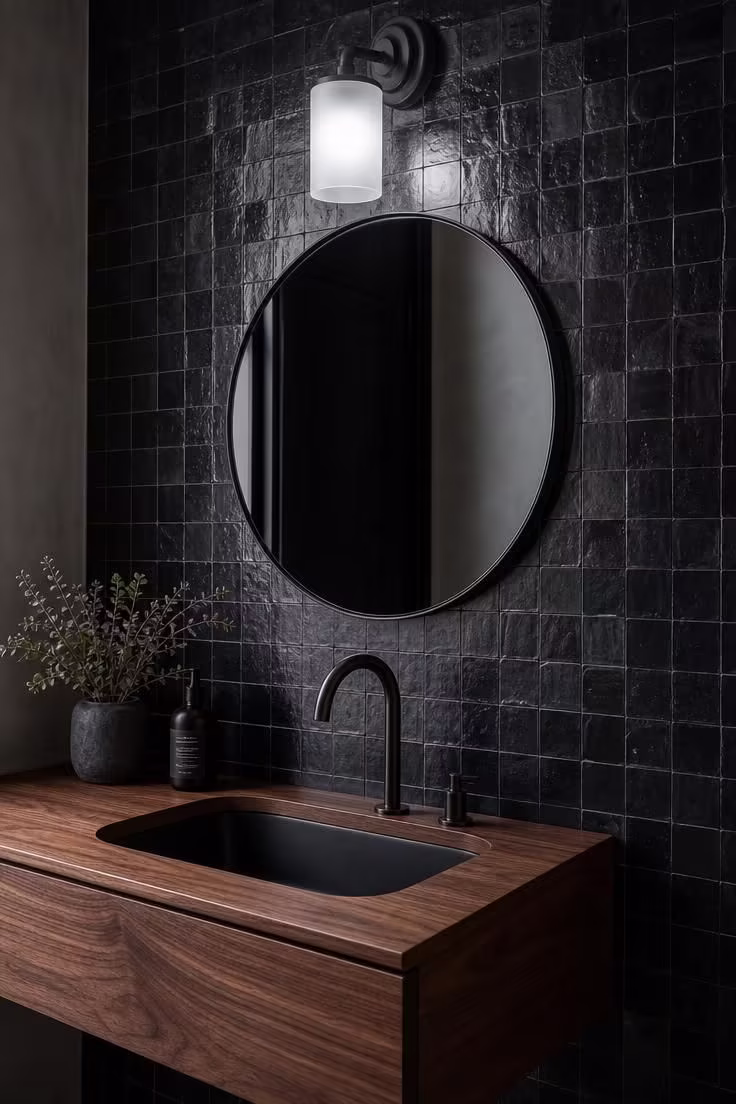 Black zellige tile wall behind a floating walnut vanity with oil-rubbed bronze faucet