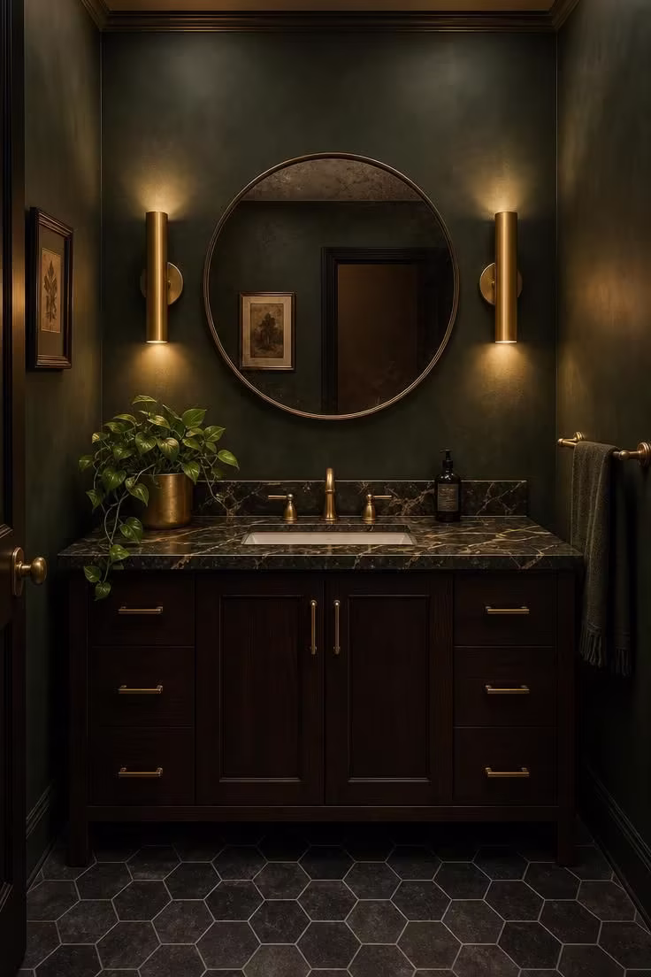 Deep forest green powder room with brushed gold sconces and dark wood vanity with marble top