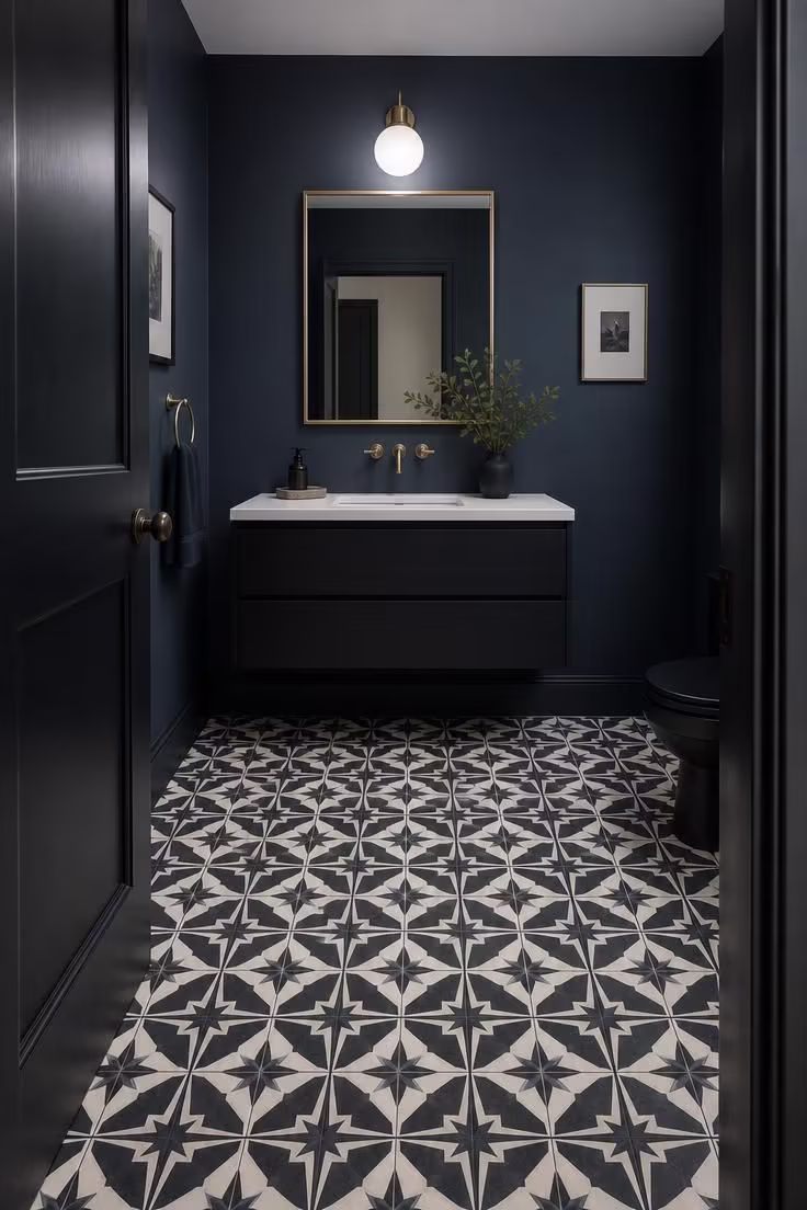 Encaustic cement tile floor with geometric pattern beneath matte black floating vanity in midnight blue powder room
