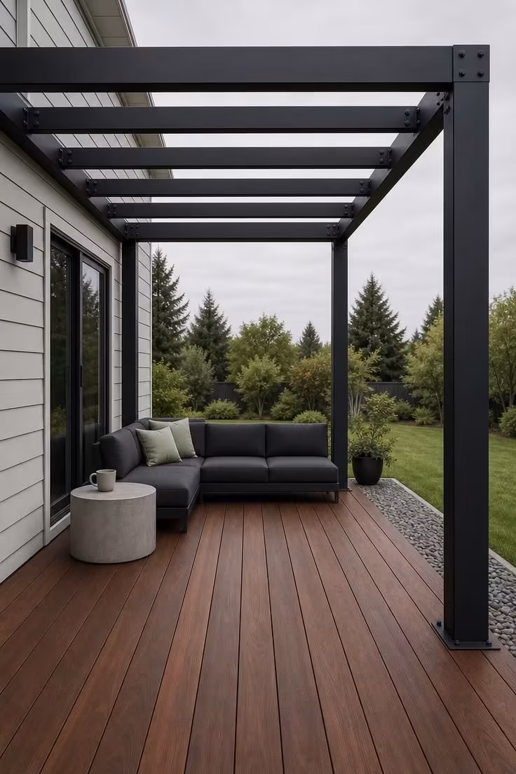 Black steel pergola over wide-plank ipe deck with overcast light and a low charcoal sectional