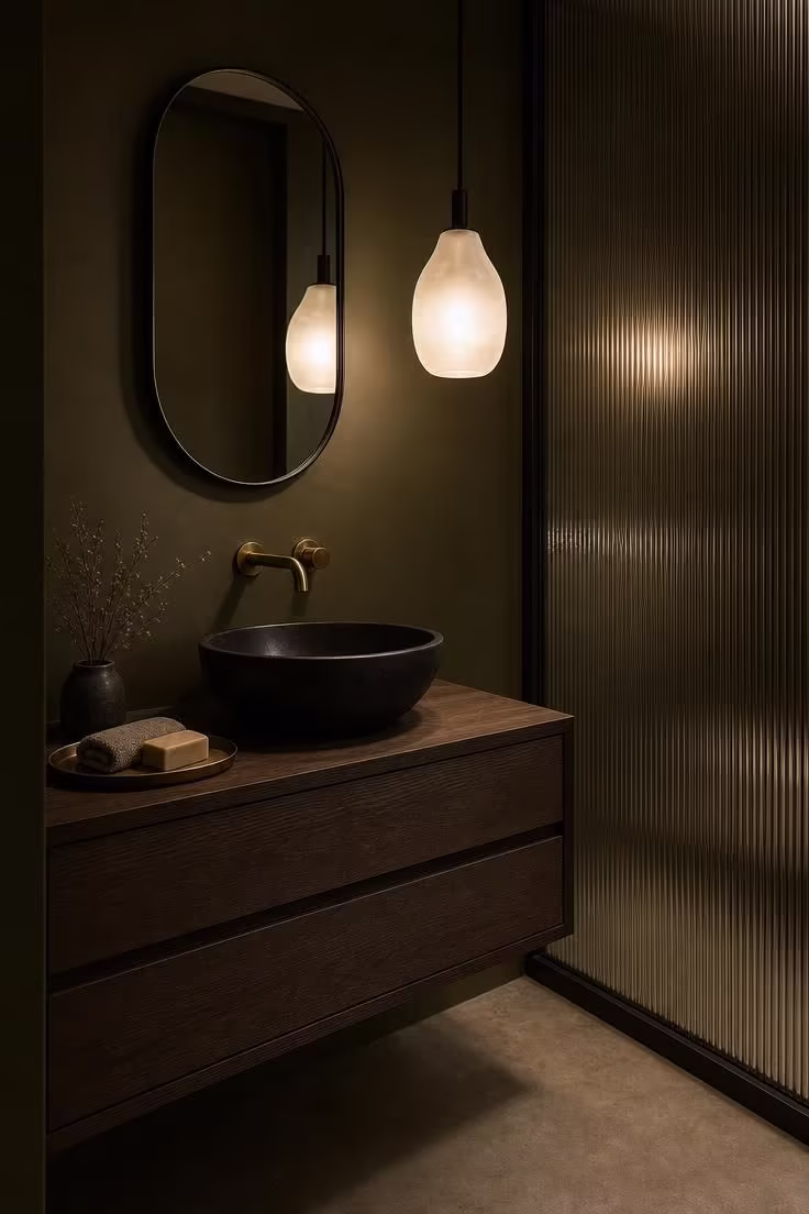 Smoked oak floating vanity with black stone vessel sink and sculptural glass pendant in dark olive powder room