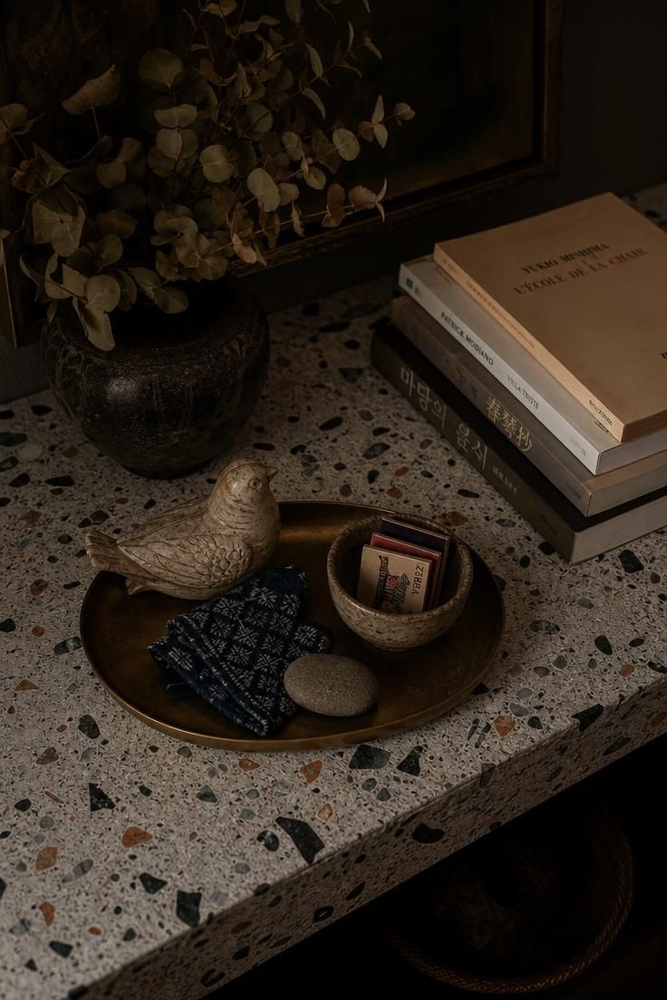Terrazzo console styled with a brass tray of travel-collected curios in low light.