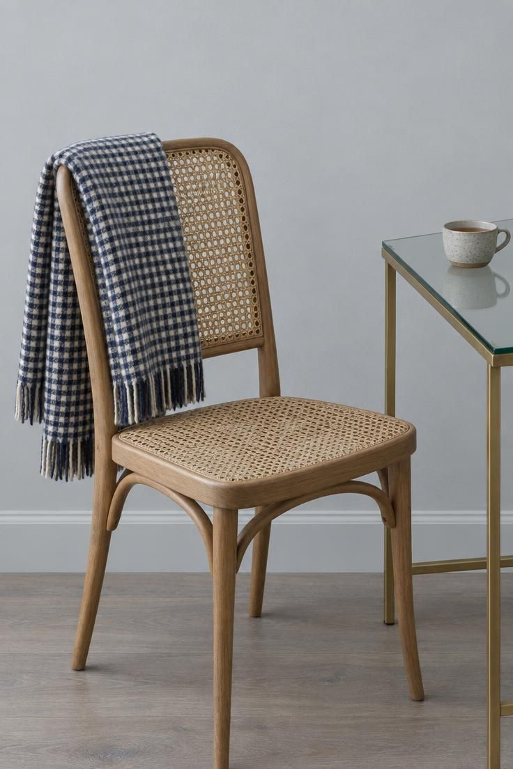 13 Warm Eclectic Home Office Ideas for Historic Rooms 8 A cane-back chair with a folded check wool throw beside a glass-topped writing table with a slim brass base.