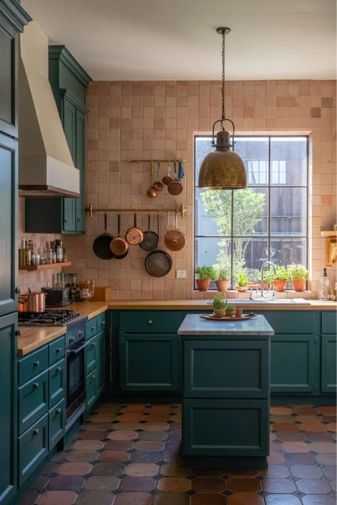 32 Eye-Catching Eclectic Kitchen Design Ideas to Love 13 Stylish eclectic kitchen with dark teal cabinetry, butcher block countertop, handcrafted terracotta tile backsplash, brass pendant light, and marble-topped island