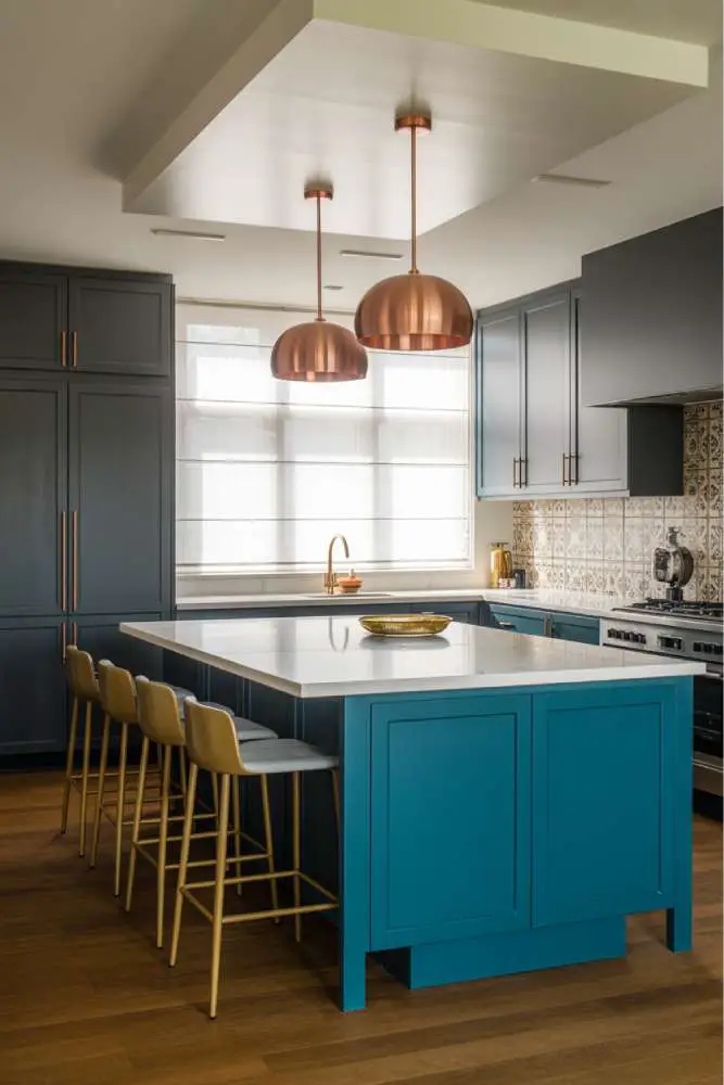 32 Eye-Catching Eclectic Kitchen Design Ideas to Love 18 Modern eclectic kitchen with vibrant teal island, white quartz countertop, brushed gold bar stools, patterned Moroccan tile backsplash, and pendant light