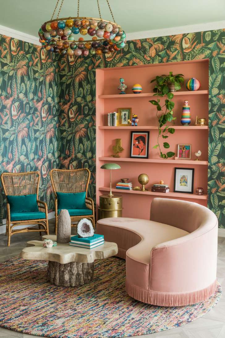 11 Vibrant Eclectic Maximalism Living Room Styles to Copy 8 Whimsical eclectic maximalism living room with tropical print wallpaper, blush curved sofa, rattan chairs, and multicolor glass chandelier
