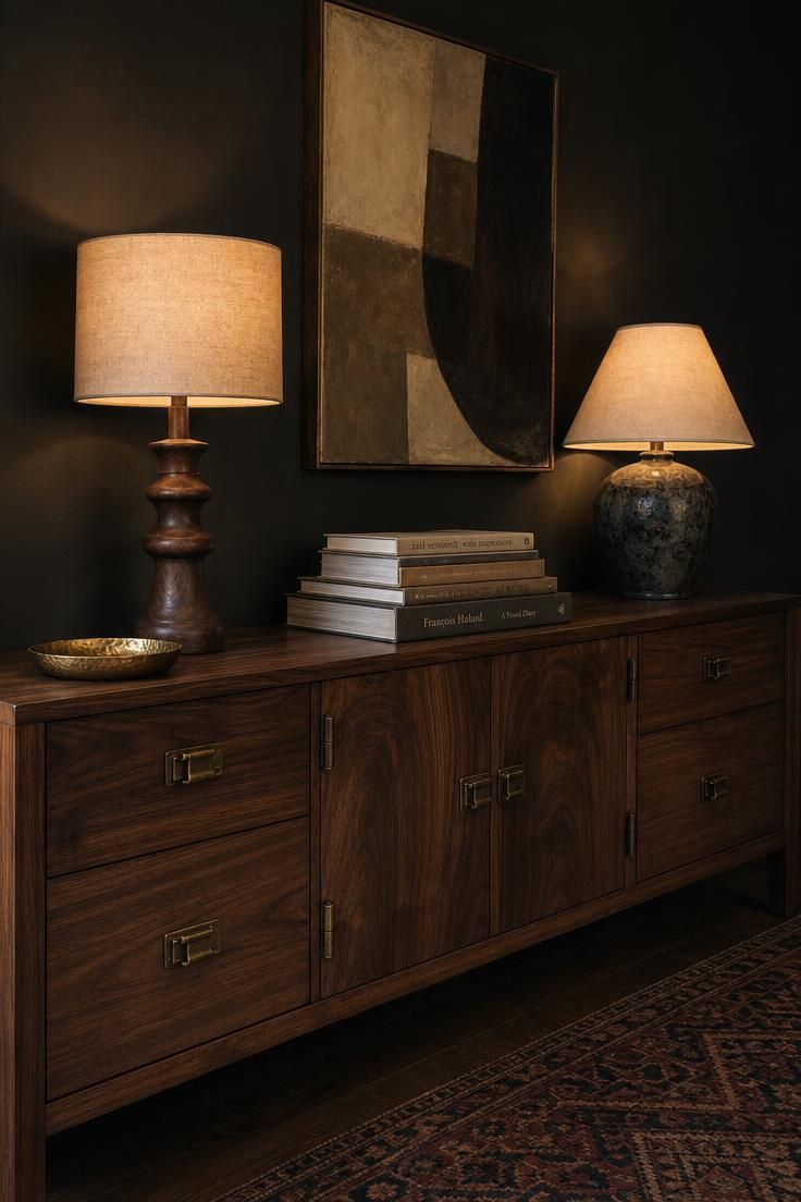 13 Eclectic Mid Century Modern Ideas for Warm Lived-In Rooms 3 A long walnut credenza with aged brass hardware under an off-center abstract painting, two mismatched lamps glowing warmly against a charcoal wall.