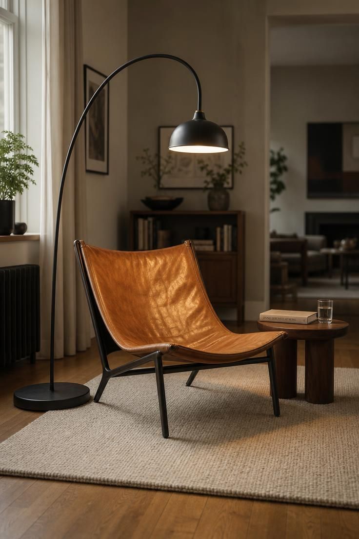 13 Eclectic Mid Century Modern Ideas for Warm Lived-In Rooms 12 A blackened steel arc floor lamp curves over a caramel leather sling chair on an oatmeal rug with a small side table, warm oak floor around.
