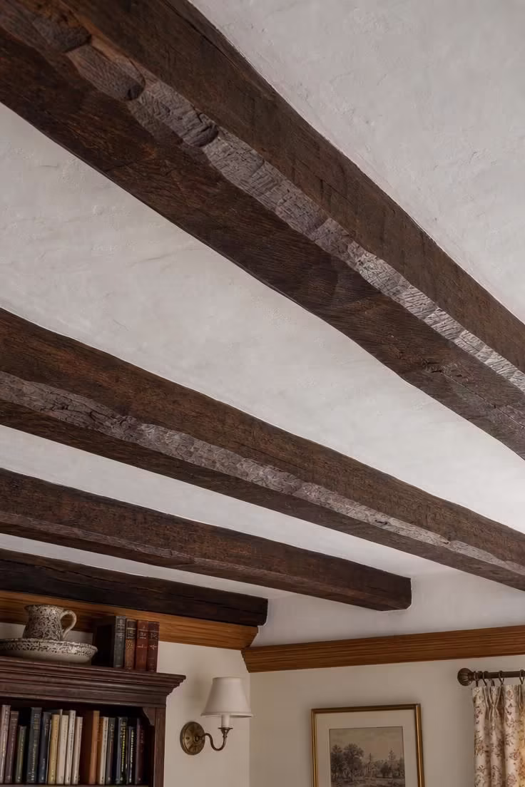 17 English Cottage Living Room Ideas Full of Character 12 Hand-hewn chestnut beams framing a low whitewashed plaster ceiling in an english cottage living room with an exposed beam ceiling.