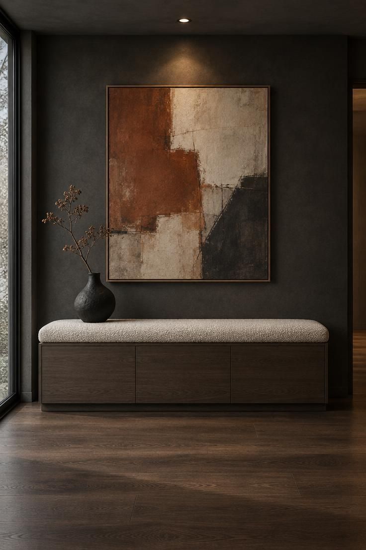 Entryway Bench Styling for a Practical and Finished Look 5 Contemporary entry bench with a bouclé cushion and smoked oak cabinet base beneath a large abstract artwork, lit by recessed and window light against a charcoal wall.