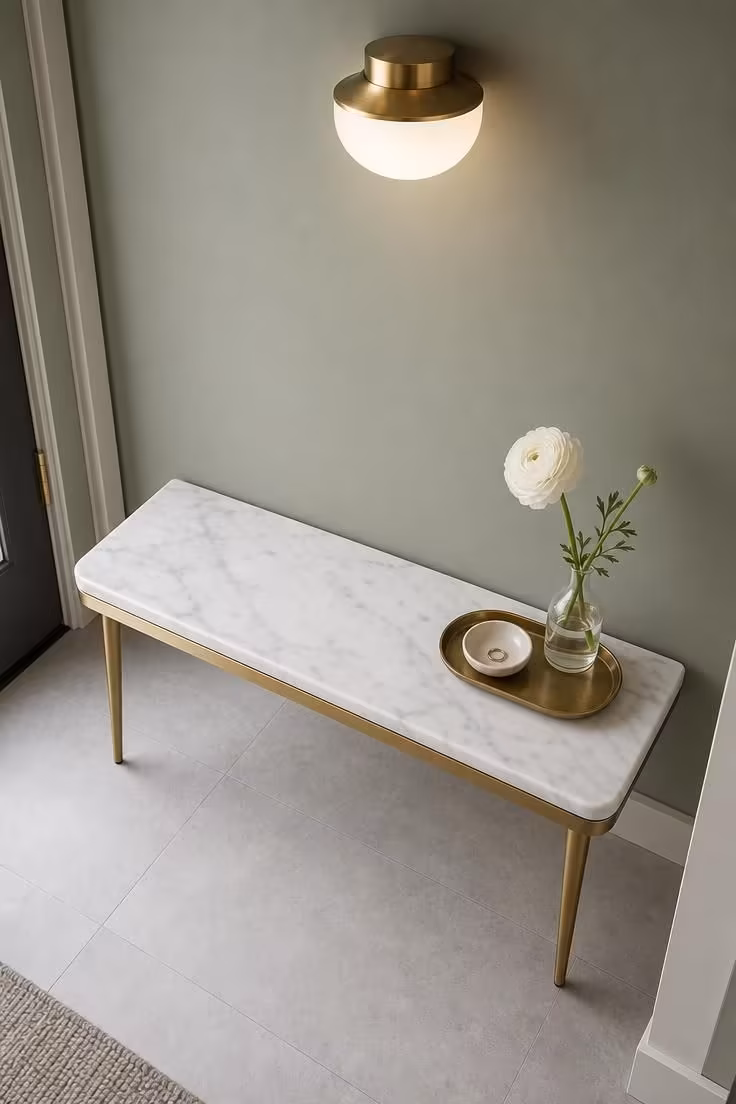 10 Charming Entryway Ideas With Bench for Every Style 7 Slim marble-top bench on brass legs against a sage green wall with a brass pendant in a modern entryway
