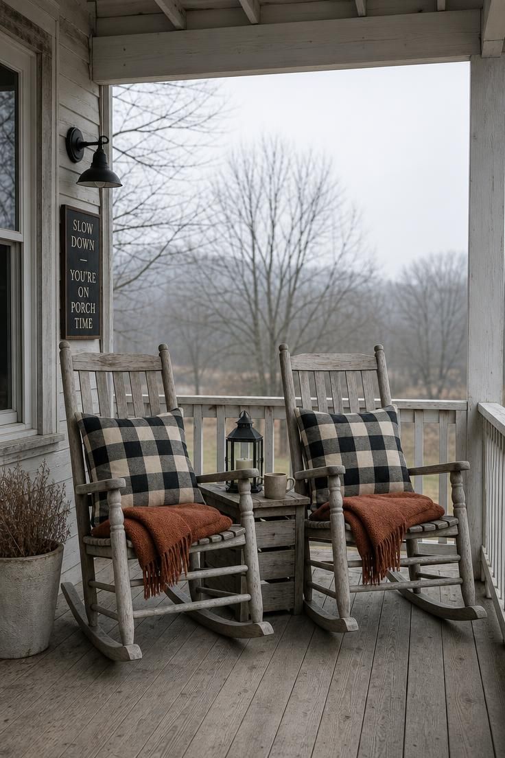 17 Cozy Fall Outdoor Decor Ideas for a Warm Welcome 12 Two weathered rocking chairs with black-and-cream buffalo-check cushions and rust throws on a porch under overcast light.