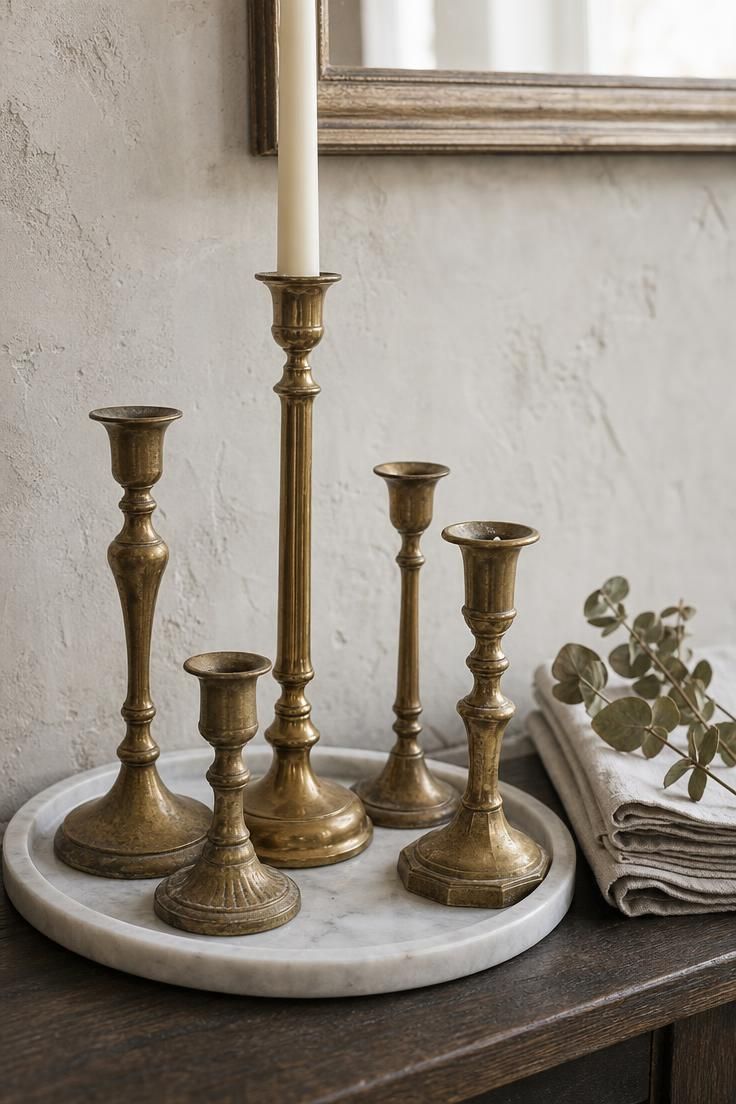 11 French Cottage Living Room Ideas Full of Soft Charm 7 Cluster of mismatched brass candlestick holders on a white marble tray in soft diffused light in a french cottage living room