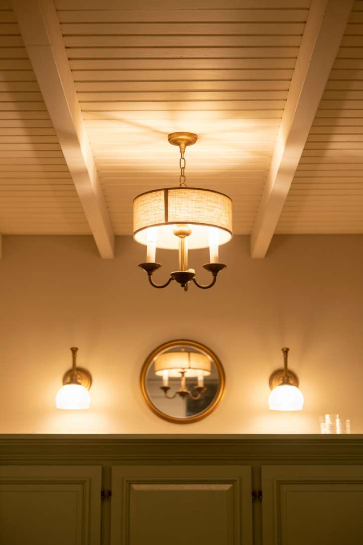 Brass drum-shade chandelier and matching wall sconces in a french country laundry room