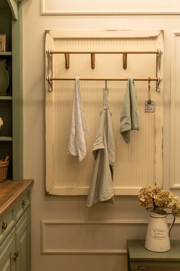 Wall-mounted beadboard drying rack with linen towels in a french country laundry room
