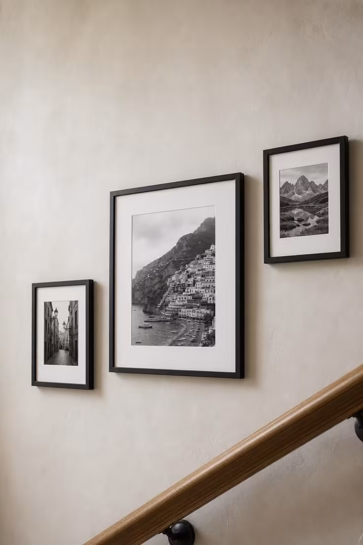 13 Warm Front Entryway Ideas With Stairs to Welcome Home 8 Black-framed photographs in a gallery arrangement ascending a plaster stairway wall in a front entryway