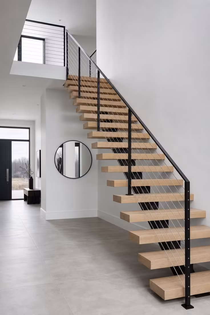 13 Warm Front Entryway Ideas With Stairs to Welcome Home 9 Modern cantilevered staircase with horizontal cable railing and matte black posts in a cool, open front entryway