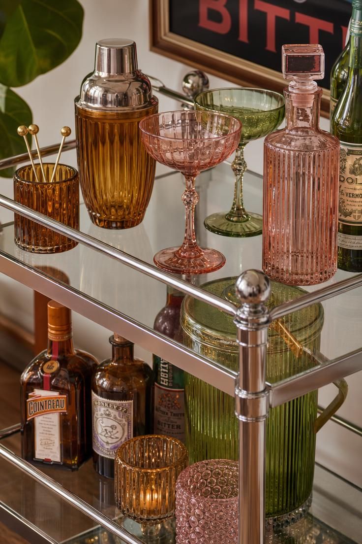 11 Playful Funky Eclectic Decor Ideas for Fearless Rooms 6 Chrome and glass bar cart styled with colored glassware against a blush pink wall.