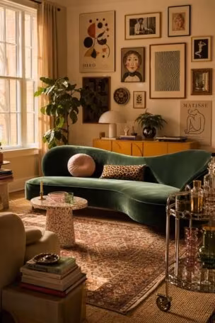 Cozy funky eclectic decor living room with an emerald velvet sofa, terrazzo table, and gallery wall under warm light.