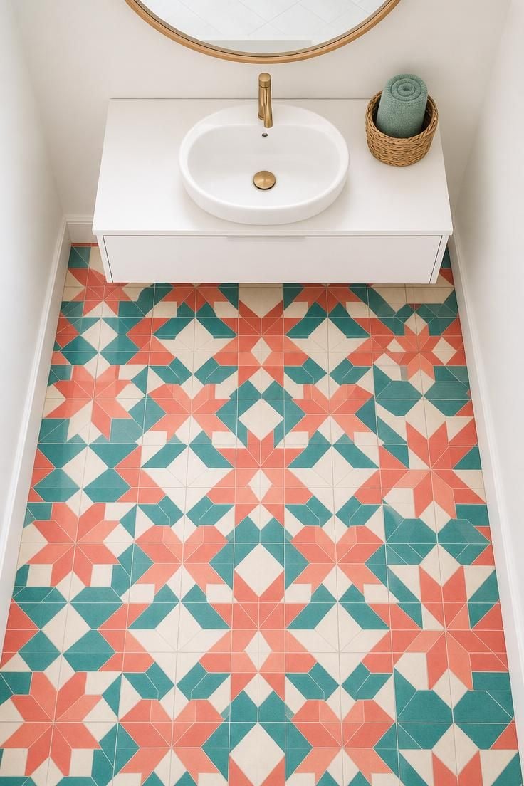 Overhead view of a powder room floor covered in coral and teal geometric cement tile with a white floating vanity and bright midday light from above.
